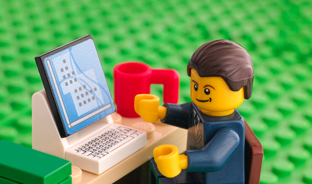 Lego man sat at laptop with red cup